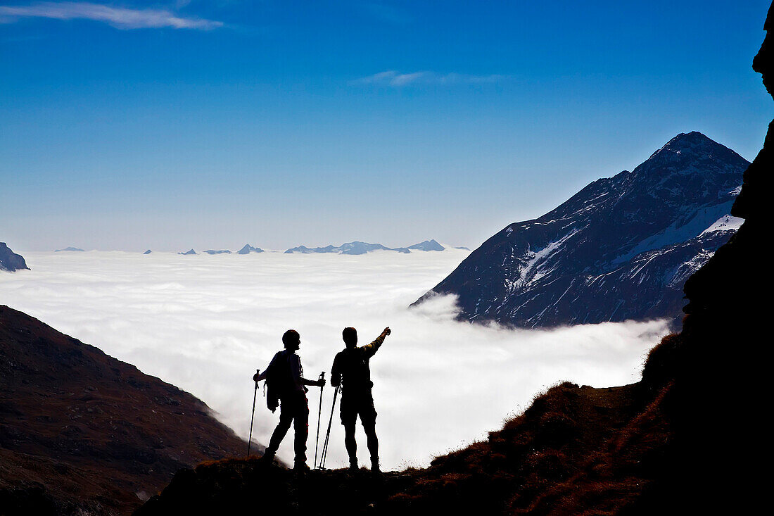 Two trekkers hike above the clouds, Engadina, Swiss alps, Switzerland