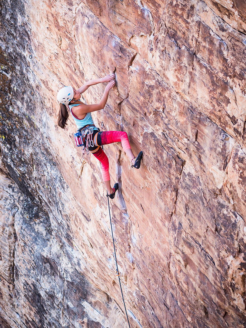 Mixed race girl rock climbing on cliff