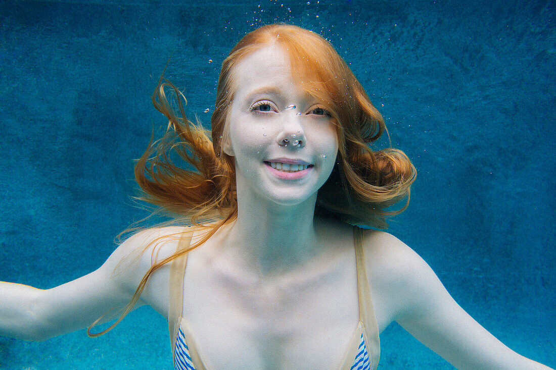 Caucasian woman smiling underwater in swimming pool