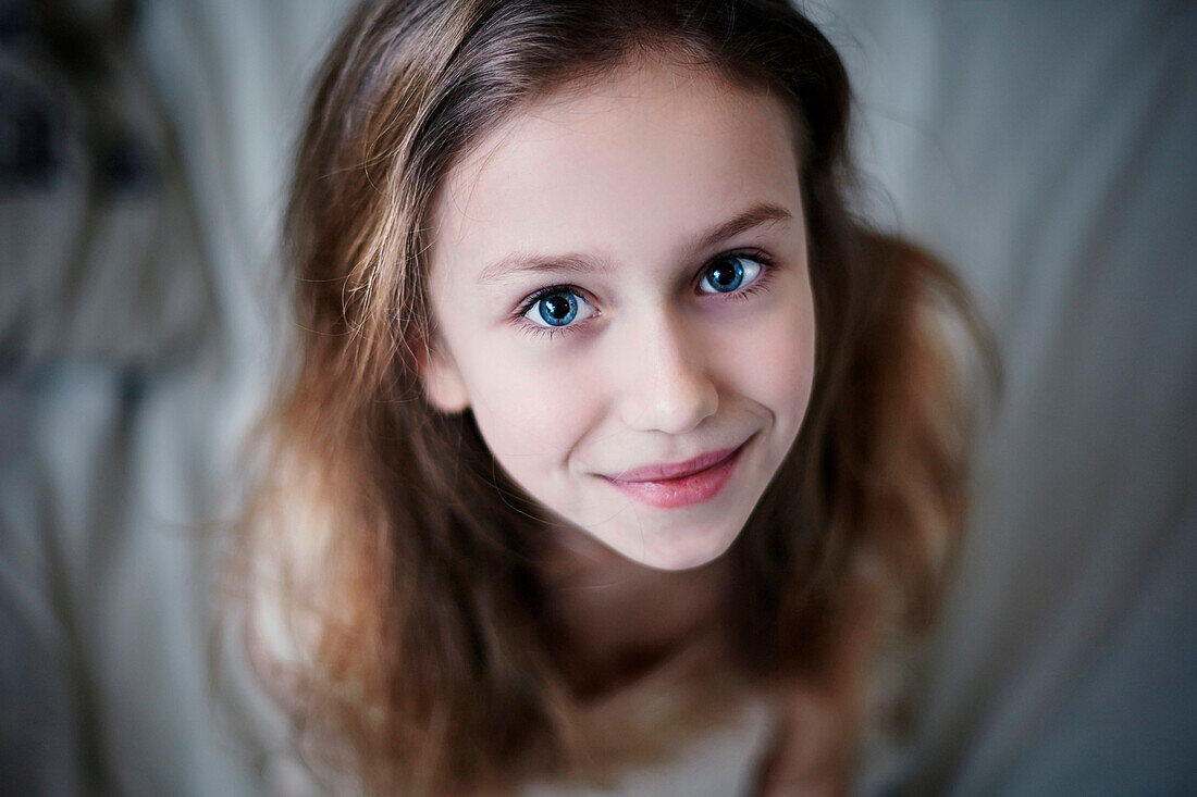 Caucasian teenage girl smiling on bed