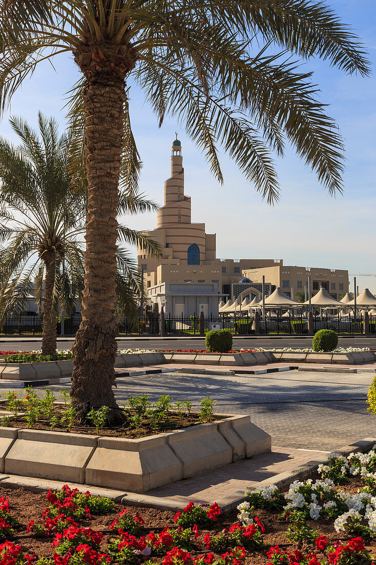 Palm trees and flower beds along Al-Corniche, waterfront promenade, with Qatar Islamic Cultural Centre, Doha, Qatar, Middle East