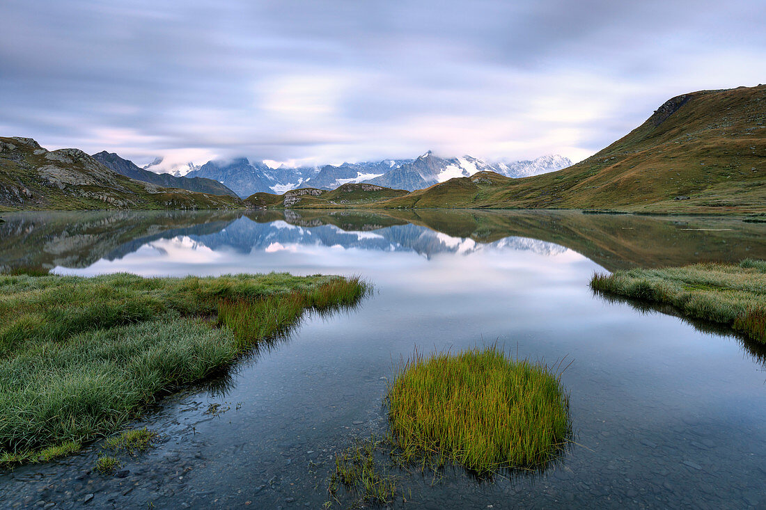 The mountain range is reflected in Fenetre Lakes at dusk, Ferret Valley, Saint Rhemy, Grand St Bernard, Aosta Valley, Italy, Europe