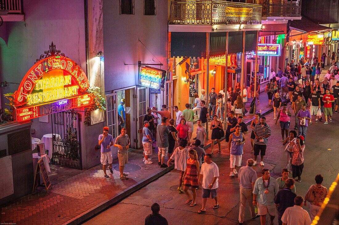 Tourists crowd Bourbon Street in New Orleans´ French Quarter at twilight, looking for nightlife.