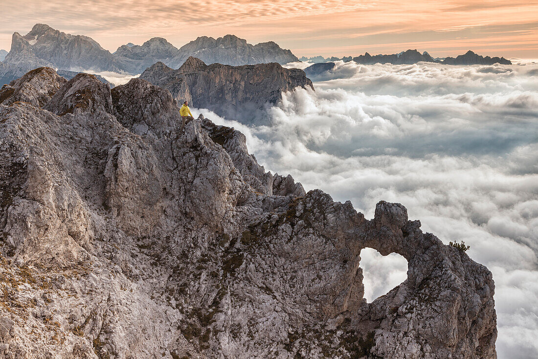 Europe, Italy, Veneto, Belluno, Agordino, Pale dei Balconi, Dolomites. Rock arch heart shaped in the Pale di San Martino over a sea of clouds.