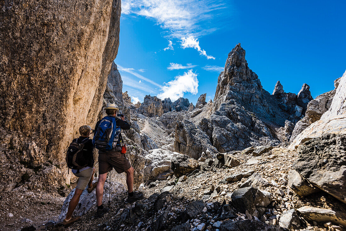 Two hiker in the mountains in the Latemar take souvenir pictures on the way to Torre die Pisa, Pampeago, the Dolomites, South Tirol, Alto Adige, Italy