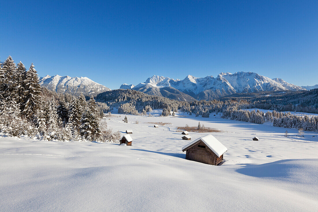 Winterlandschaft mit Heustadeln am Geroldsee, Blick auf Soierngruppe und zum Karwendel, Bayern, Deutschland