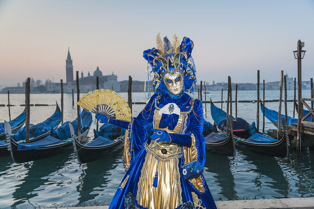 A masked woman at the carnival in Venice with gondolas in the background, Italy, Europe