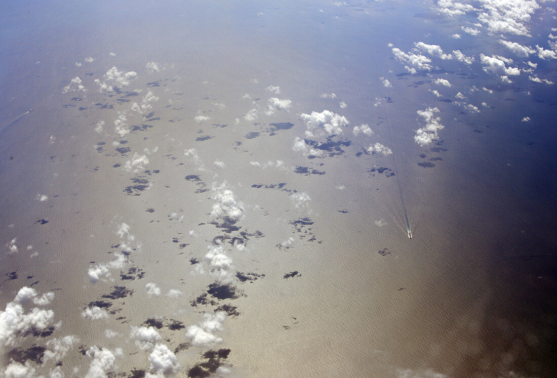 Wolken über Meer mit Frachtschiff vom Flugzeug