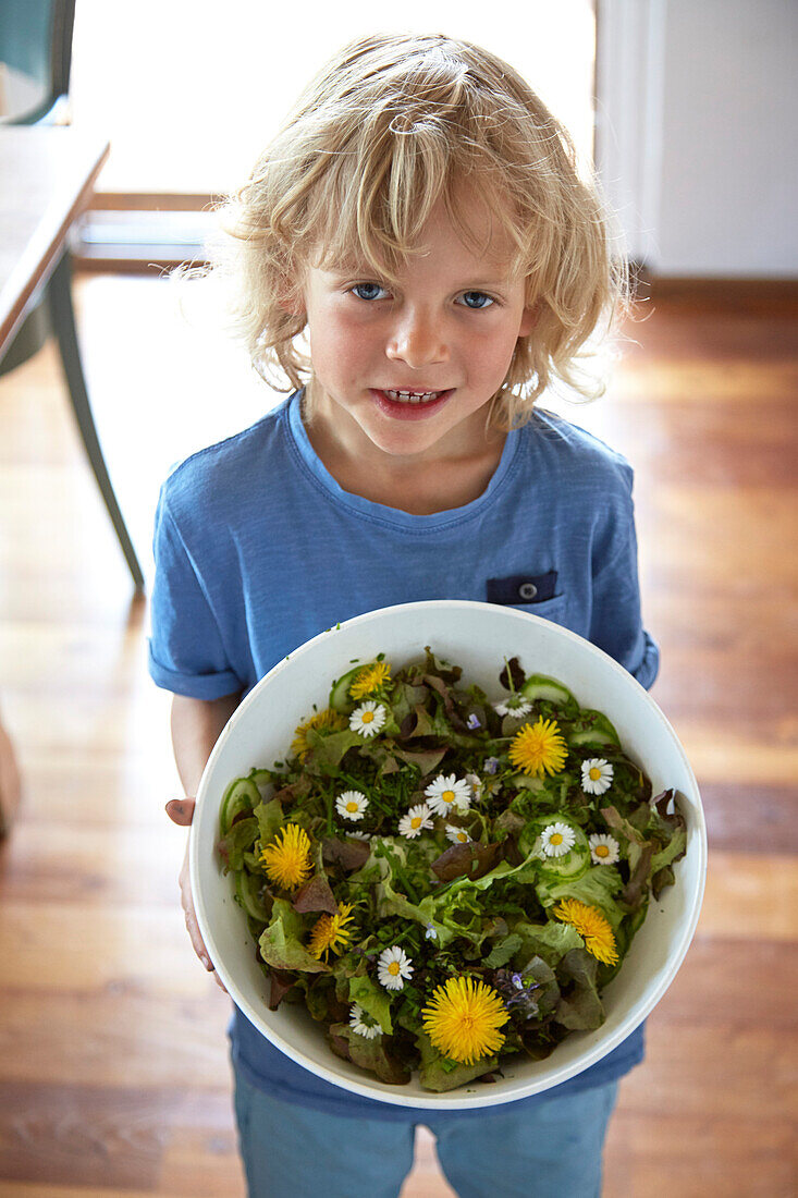 Junge hält Schüssel mit frischem Wildkräutersalat