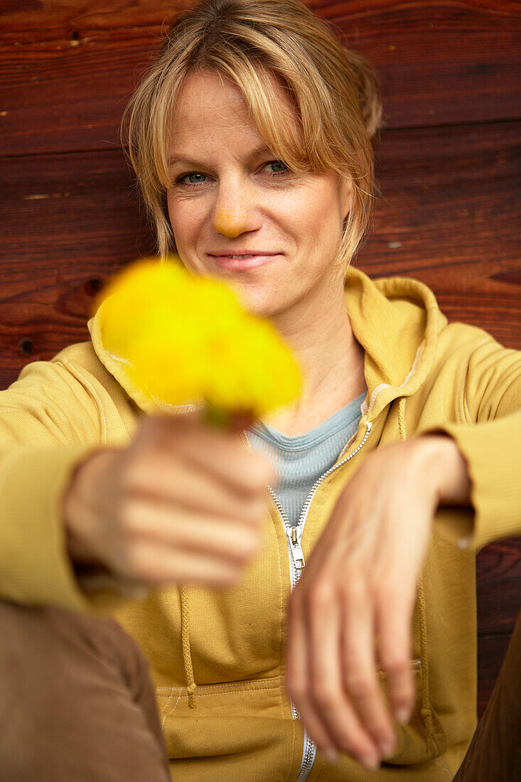 Woman with hawkbit in front of a wooden wall