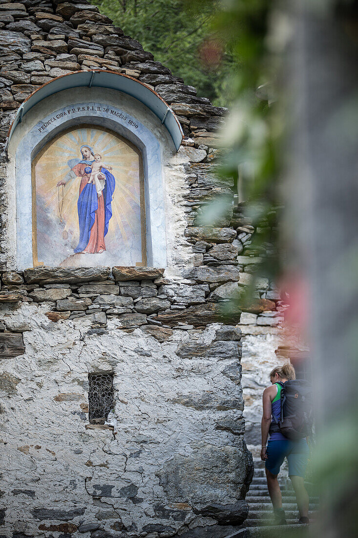 Young female hiker walking through an old village, Valle Verzasca, Ticino, Switzerland