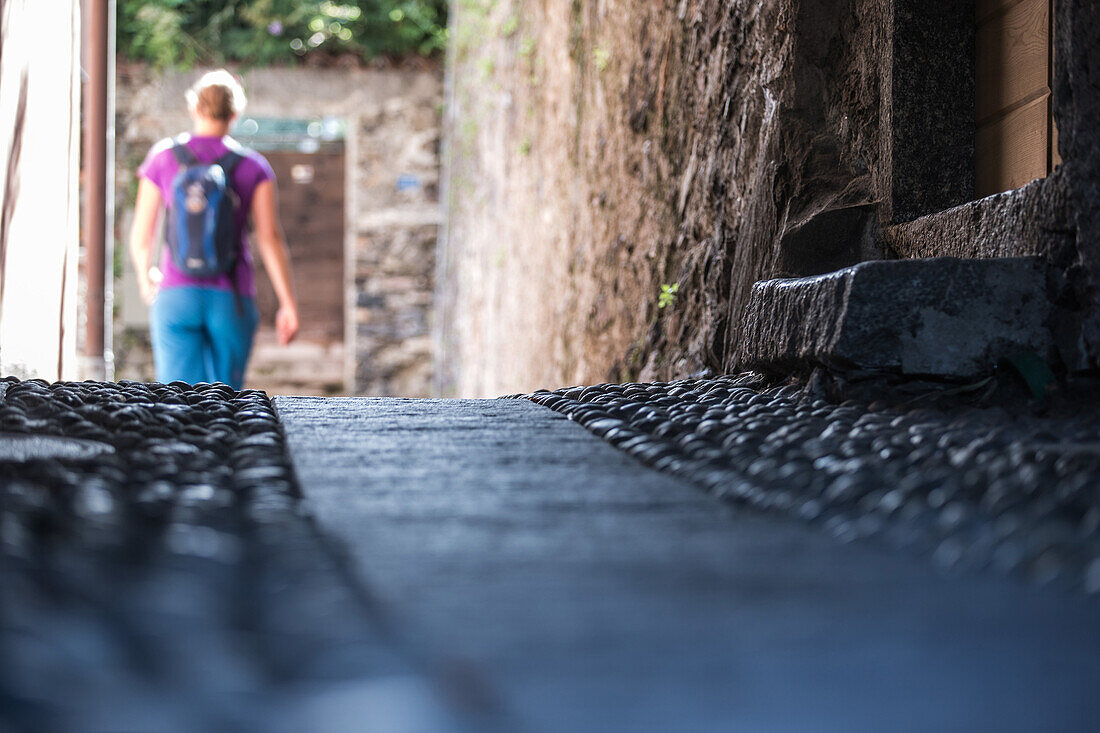 Young female hiker walking through an old town, Ronco, Ticino, Switzerland