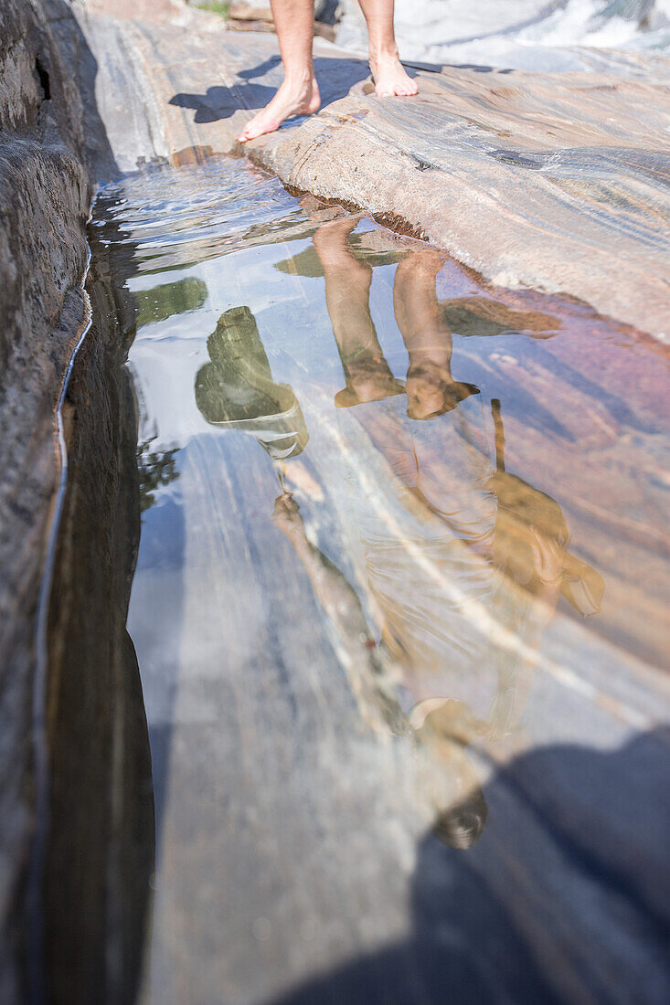 Junge Wanderin geht auf Felsen ziwschen einem Fluss, Val Verzasca, Tessin, Schweiz