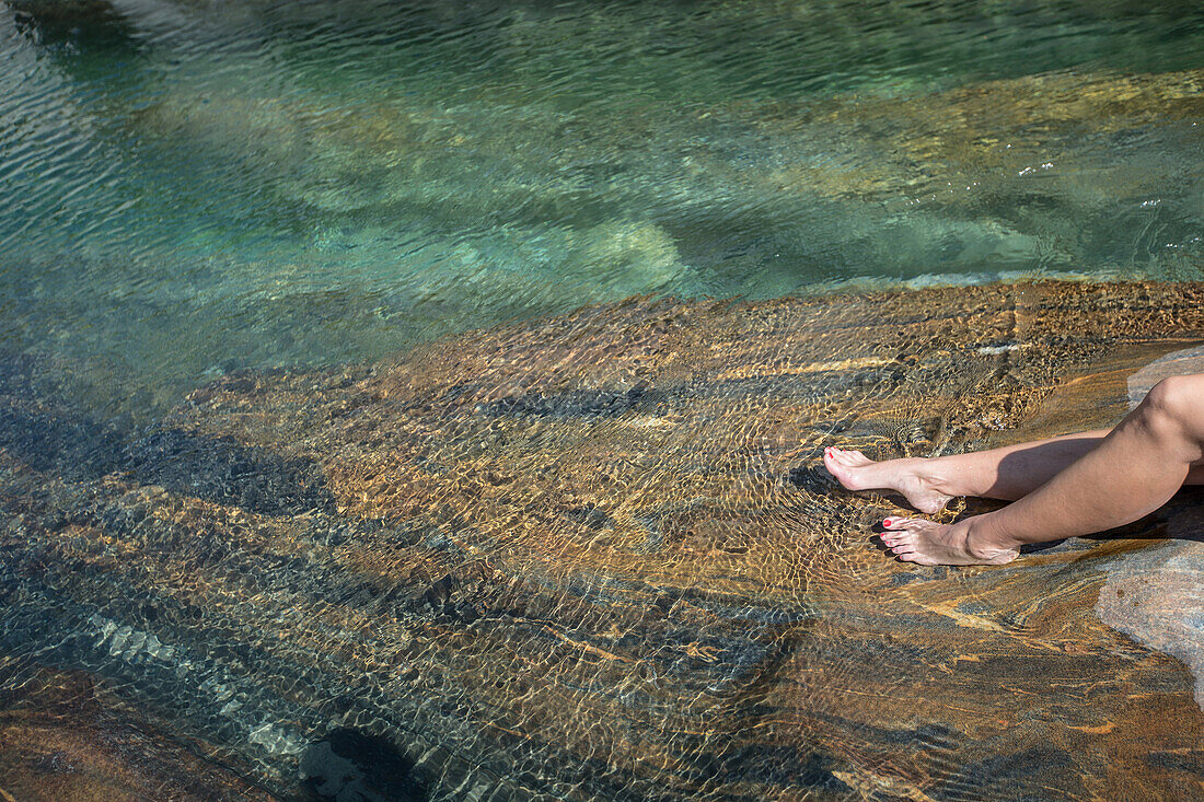 Young female hiker lying on a rock at a river, Valle Verzasca, Ticino, Switzerland