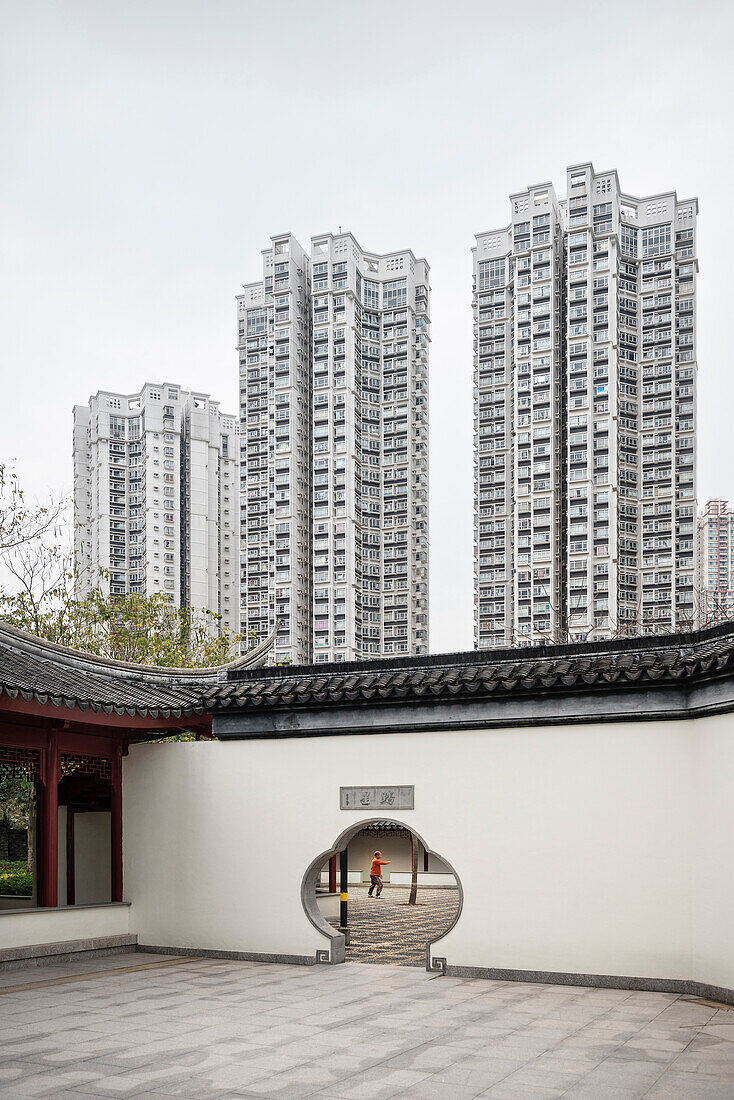old Chinese Man does Tai Chia Qigong in temple in front of modern project housing, Tin Shu Wai, Hongkong, China, Asia