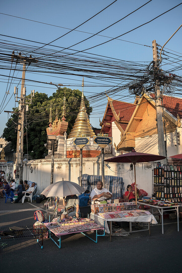 vendor sits in front of temple during market, Chiang Mai, Northern Thailand, Southeast Asia