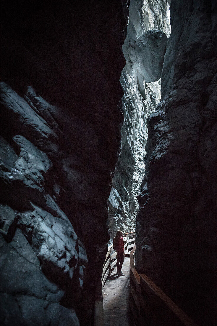 junge Frau blickt in Vorderkaserklamm nach oben, wo zwischen den Felsen ein großer Felsblock eingeklemmt ist, Salzburger Land, Österreich, Europa