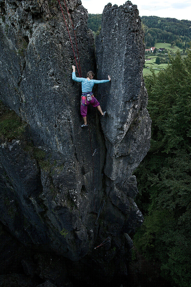 Young woman climbing at a rock face, Pottenstein, Franconia, Germany