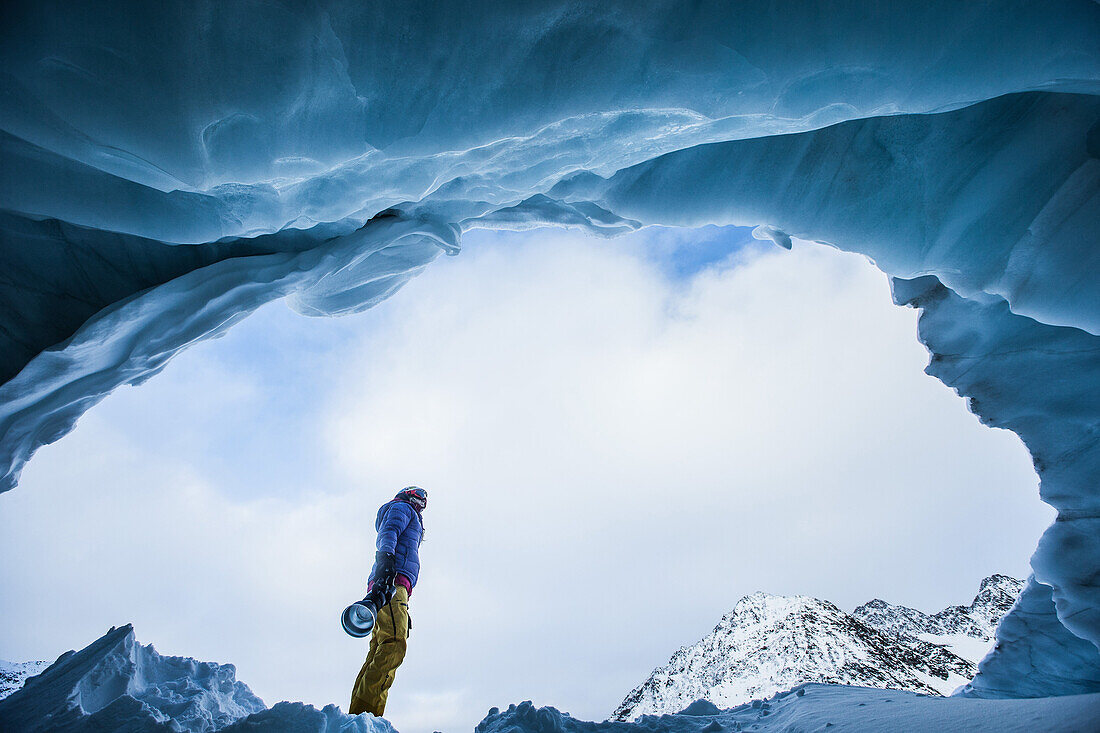 Junge Skifahrerin steht in einer Gletscherhöhle in den Bergen, Pitztal, Tirol, Österreich