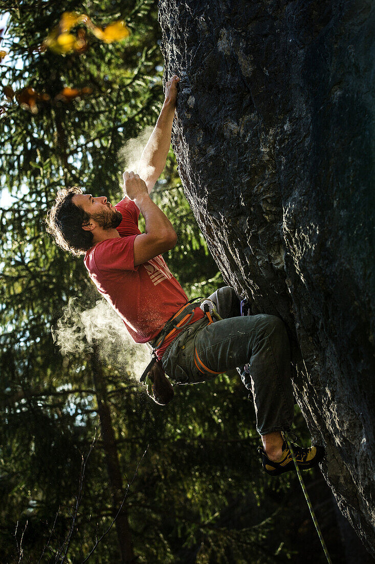 Junger Kletterer pustet das Magnesium von seiner Hand an einer Felswand, Schwaerzer Wand, Bayern, Deutschland