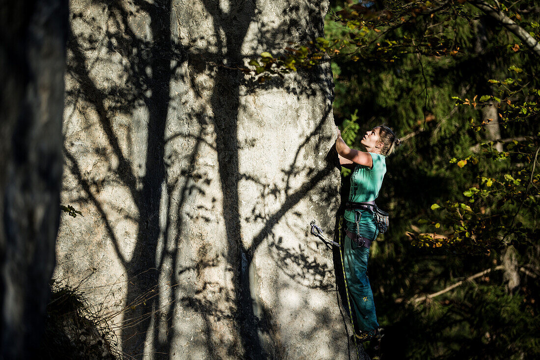 Young woman climbing at a rock face, Schwaerzer Wand, Bavaria, Germany