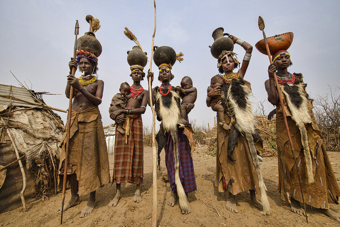 Dassanech women with hyena pelt skins and jugs on their heads in the Lower Omo Valley of Ethiopia.