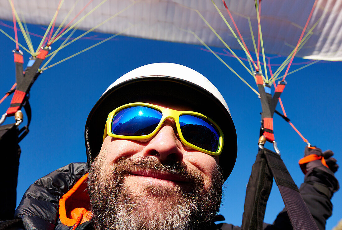An adult caucasian man while paragliding.