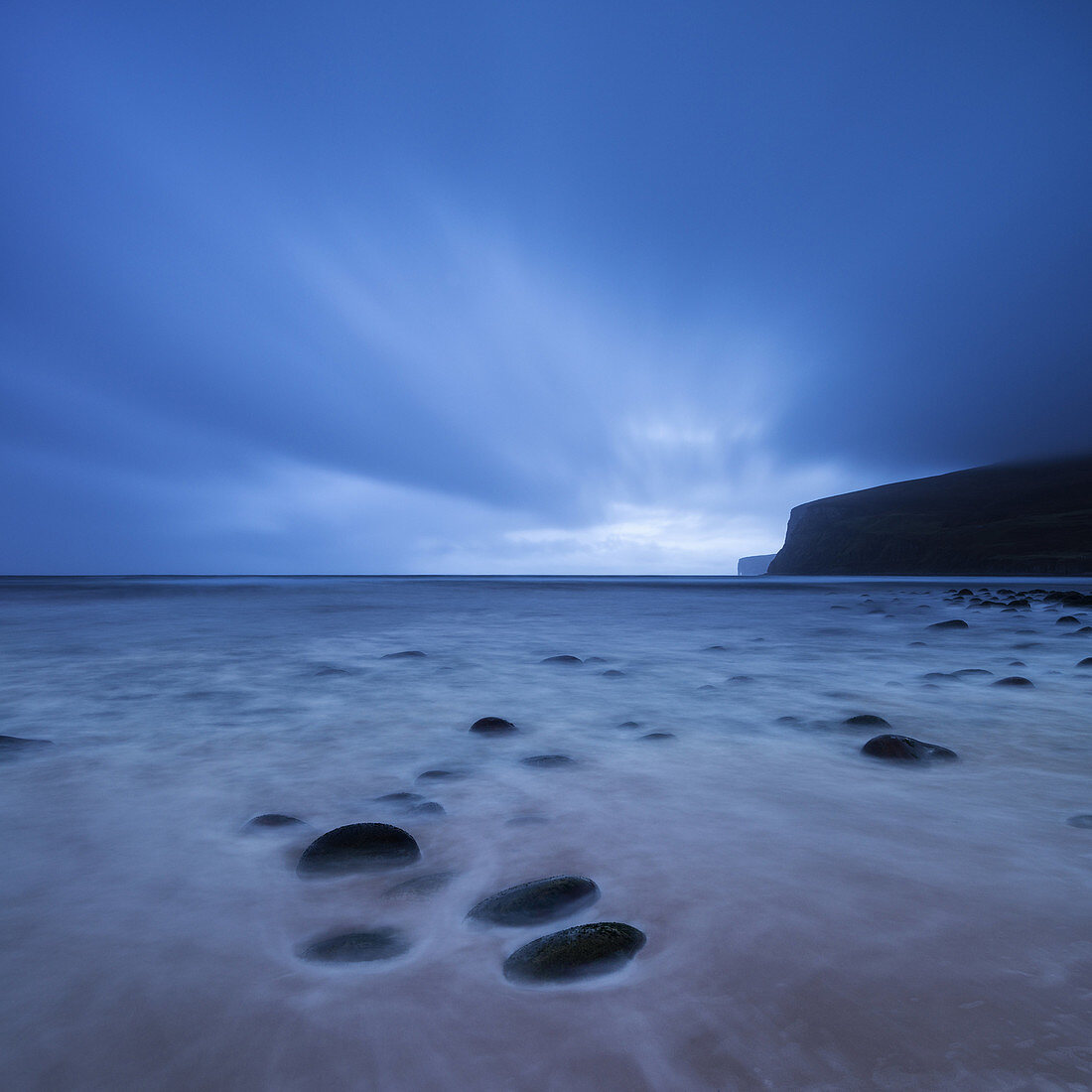 Clouds sweep across sky in fading light over beach at Rackwick Bay, Hoy, Orkney, Scotland.