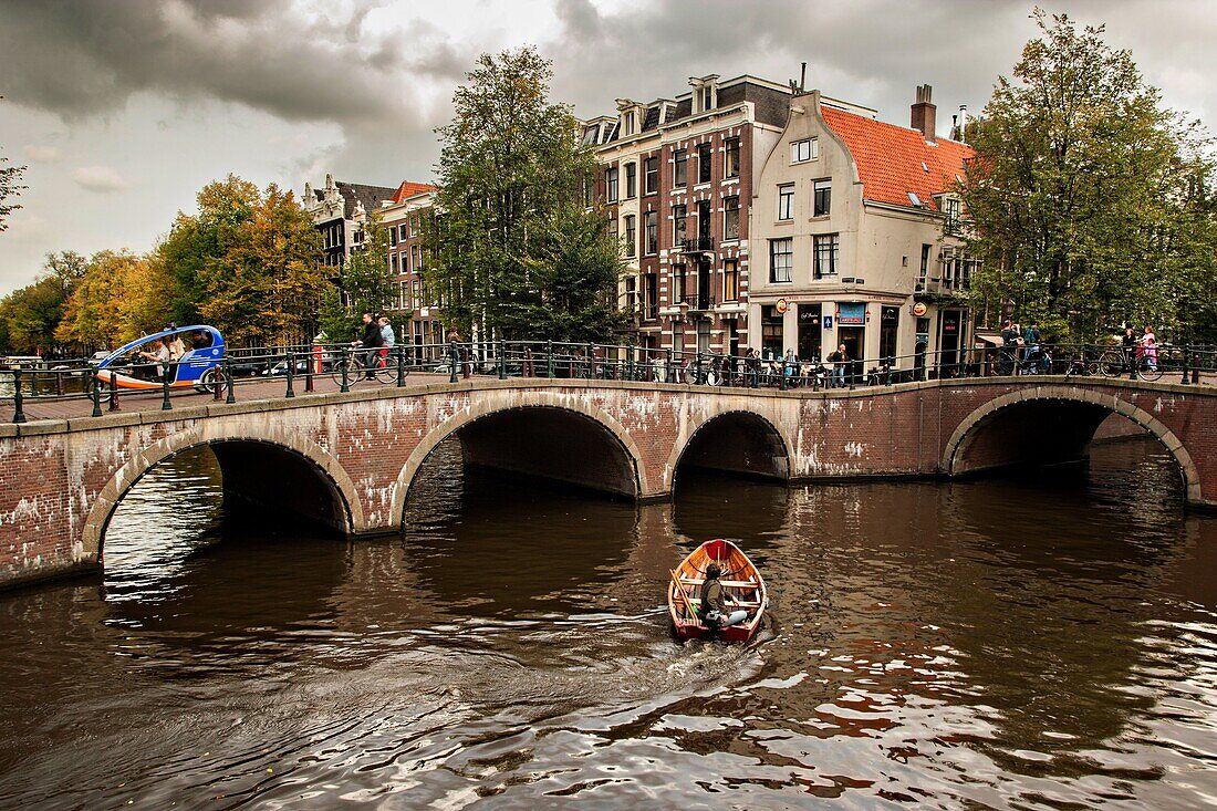 A boat passes the Hemonybrug bridge at Keizersgracht and Leidsegracht in the Singel Canel in Amsterdam.