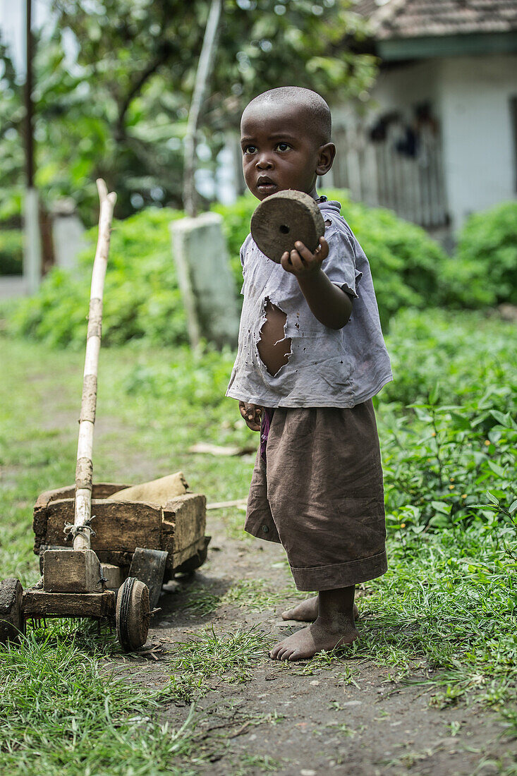 Kleiner einheimischer Junge hält das hölzerne Rad seines einfachen Spielzeugs in der Hand, Sao Tome, Sao Tome und Príncipe, Afrika