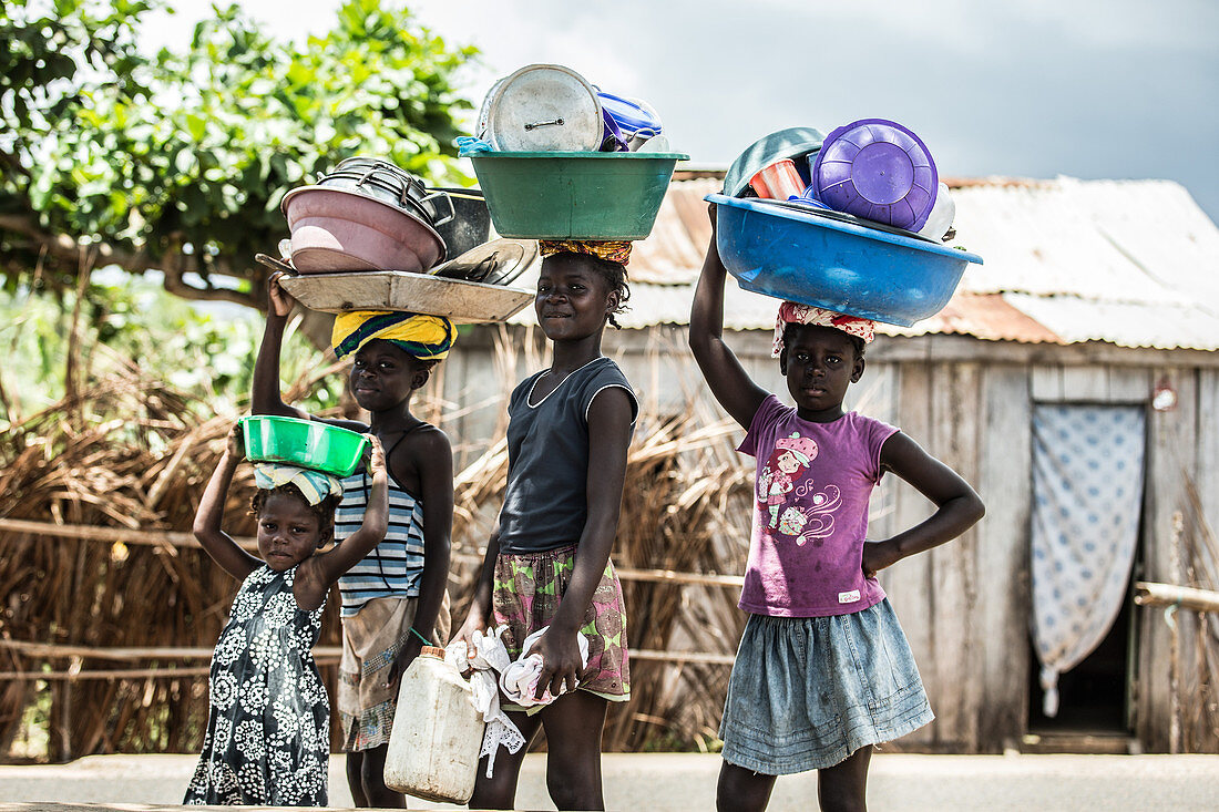 Kleine einheimische Kinder tragen ihre Geschir in Schüsseln auf ihrem Kopf, Sao Tome, Sao Tome und Príncipe, Afrika