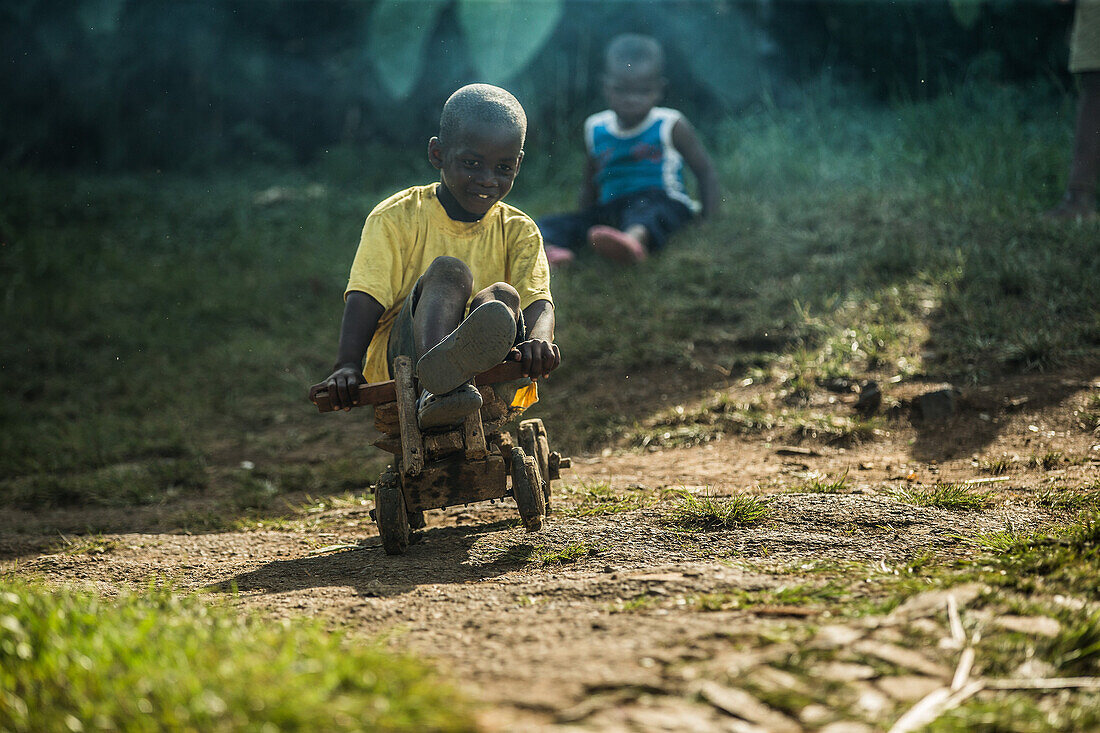Kleiner einheimischer Junge fährt auf einem einfachen hölzernen Spielzeugwagen, Sao Tome, Sao Tome und Príncipe, Afrika