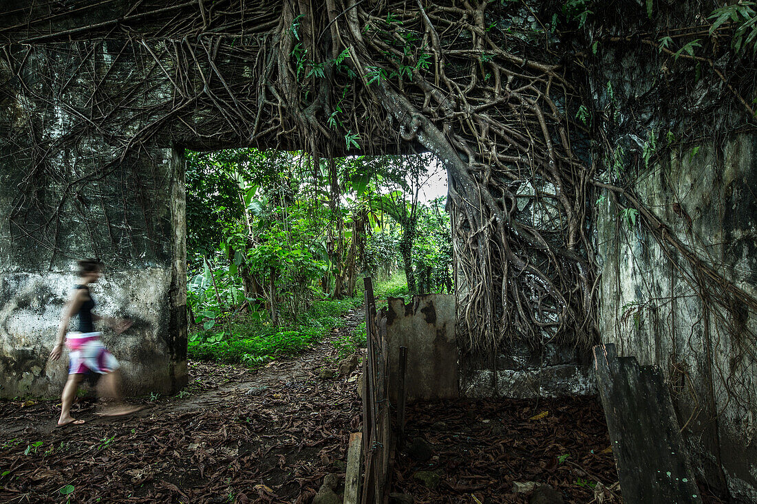 Junge Frau geht durch eine überwachsene Ruine/ Sao Tome, Sao Tome und Príncipe, Afrika