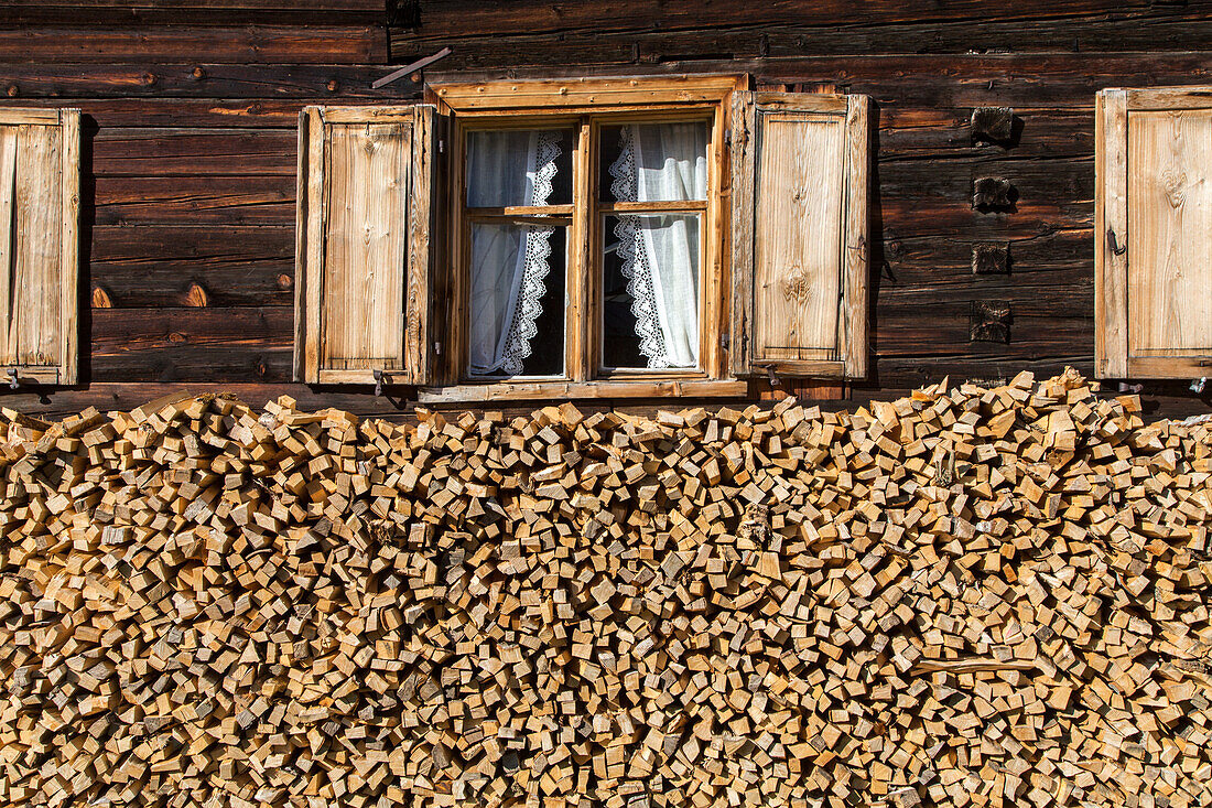 old traditional timber house, firewood stacked below windows with wooden shutters, Bregenzerwald, Vorarlberg, Austria