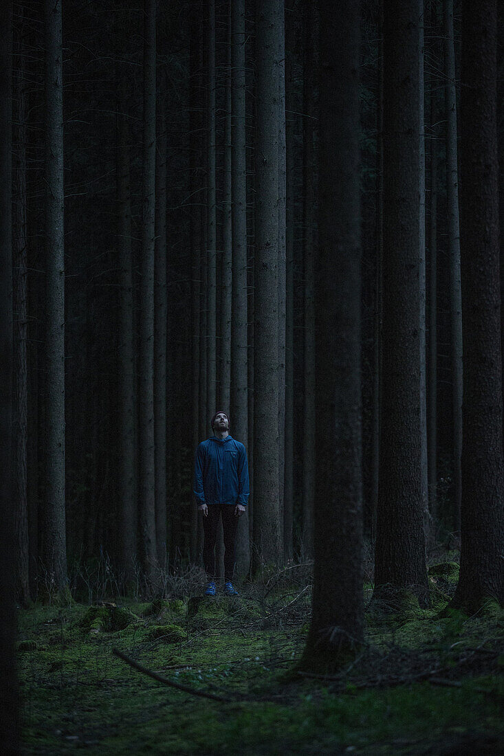 Junger Läufer steht im Wald und sieht nach oben, Allgäu, Bayern, Deutschland