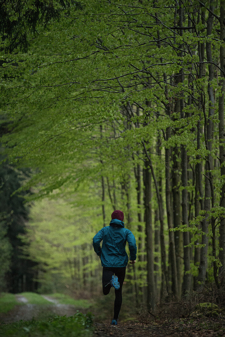 Junger Mann läuft auf einem Weg durch einen Wald, Allgäu, Bayern, Deutschland