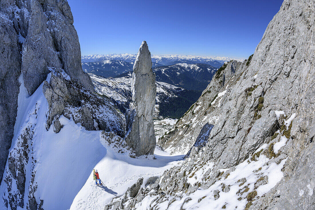 Woman back-country skiing standing in Angersteinrinne, view to spire of Angersteinmandl, Angerstein, Gosau range, Dachstein, Salzburg, Austria