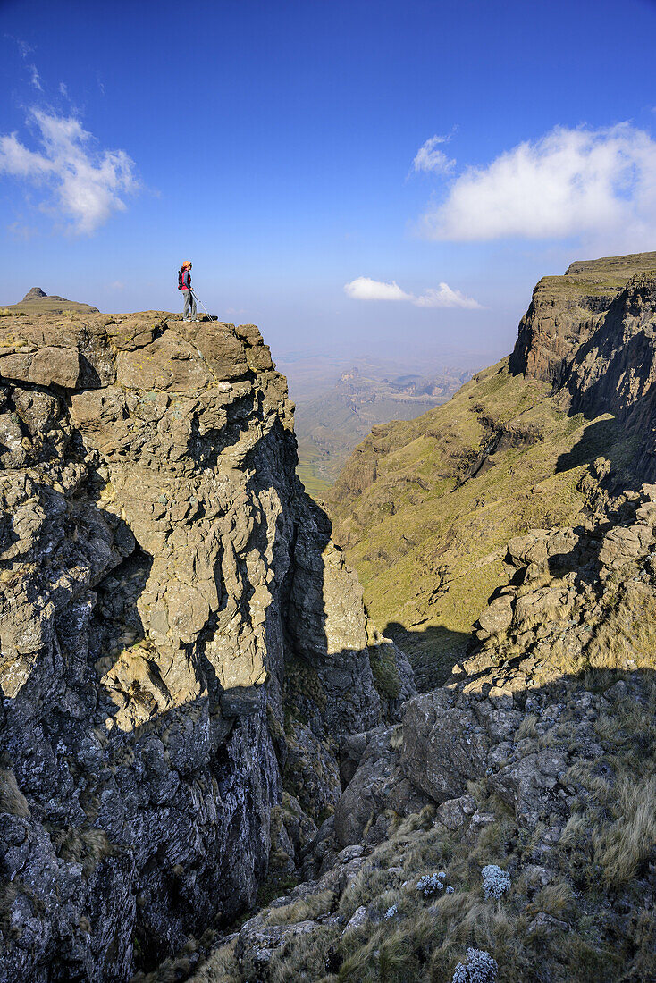 Frau beim Wandern blickt auf Felsschlucht hinab, Rhino Peak im Hintergrund, Rhino Peak, Garden Castle, Mzimkhulu Wilderness Area, Drakensberge, uKhahlamba-Drakensberg Park, UNESCO Welterbe Maloti-Drakensberg-Park, KwaZulu-Natal, Südafrika