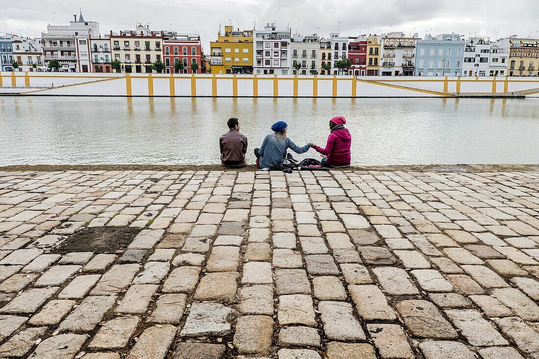 People group standing in riverside in front of Triana district. Seville, Andalusia, Spain.