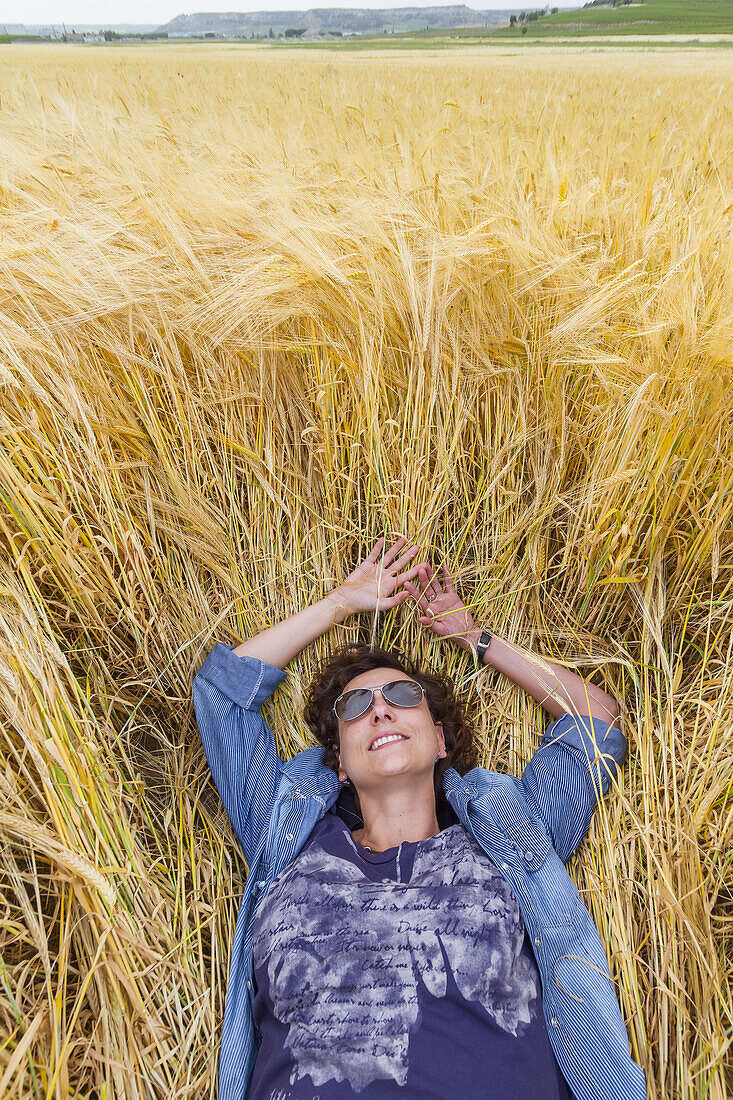 Woman resting in a wheat field. Peñafiel village. Ribera de Duero region. Valladolid. Castile and Leon. Spain, Europe.