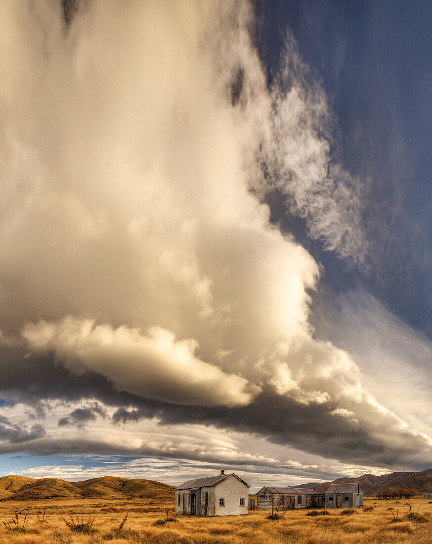 Dawn lights up cloudscape over historic (1939) farm buildings near St Bathans, Central Otago, New Zealand.