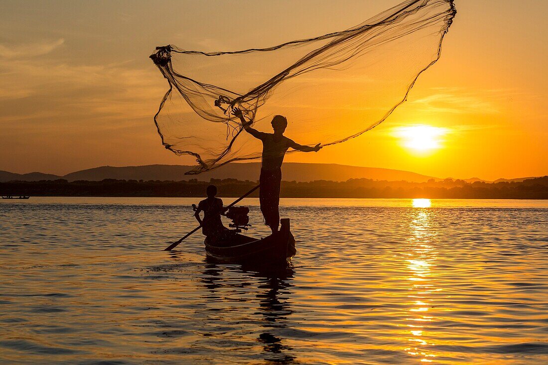 Fishermen casting out fishing nets at sunset, Mandalay, Burma.