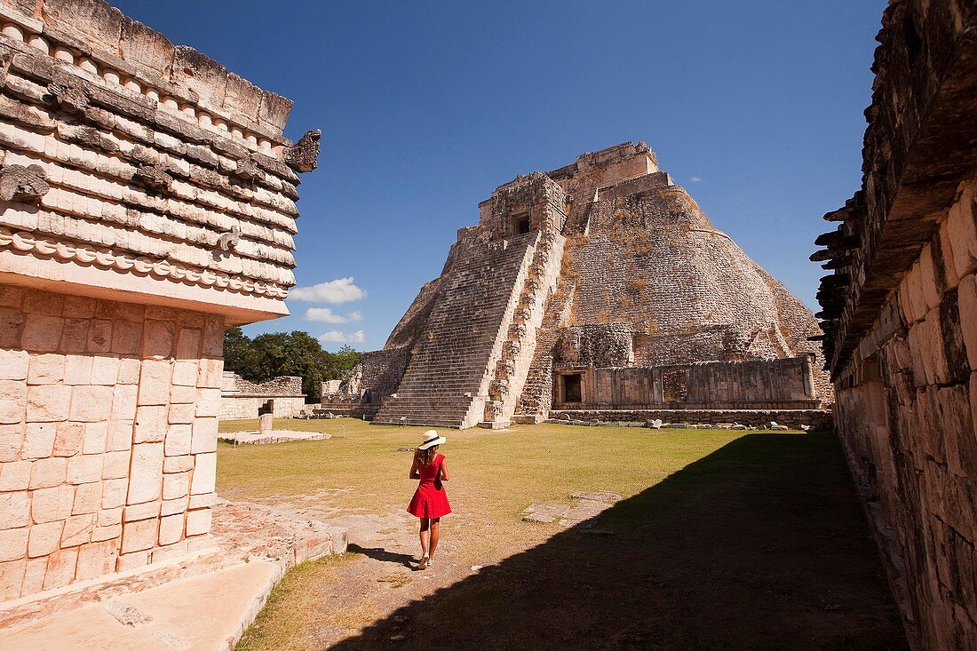 Tourist walking around the Pyramid of the Magician, Maya archeological site Uxmal, Yucatan, Mexico, Central America.