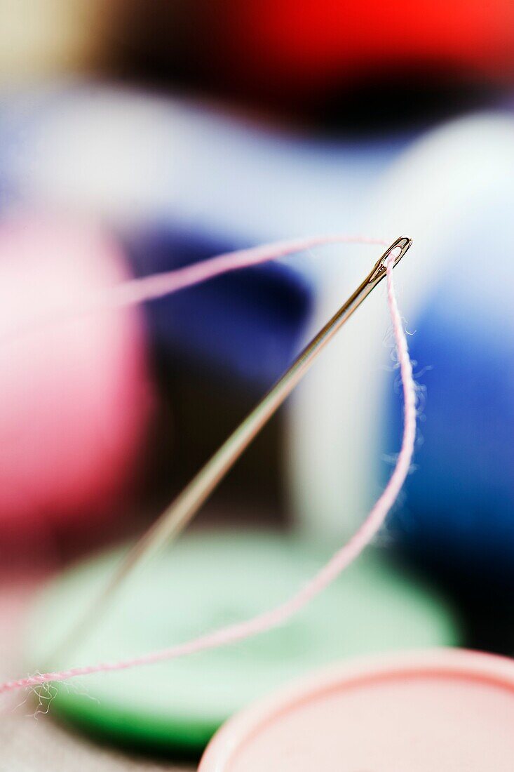 Needle threaded with pink cotton.