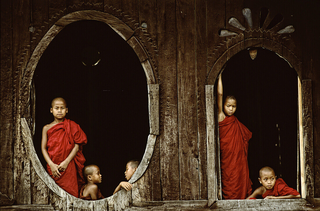 Monks in the windows of a teak monastery.Myanmar.