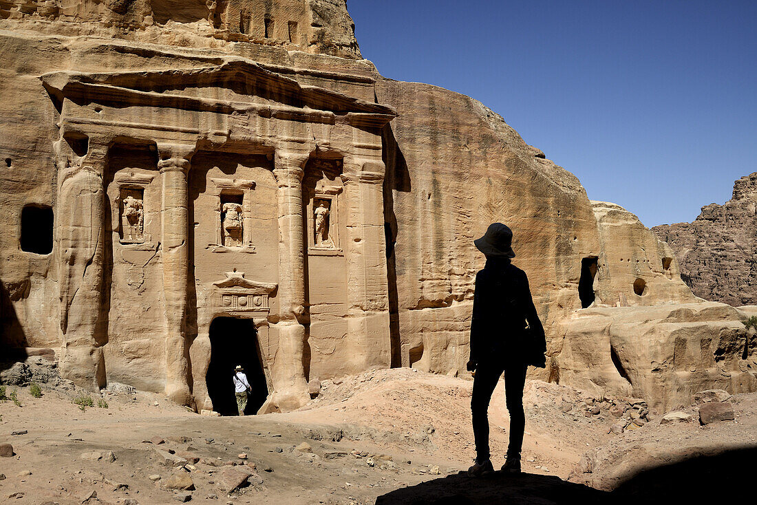 Silhouette of a woman watching the façade of the Roman Soldier´s Tomb, carved out of a sandstone rock face. Jordan (Hashemite Kingdom of), Ma´an Governorate (Maan), ancient city of Petra. Model Released.