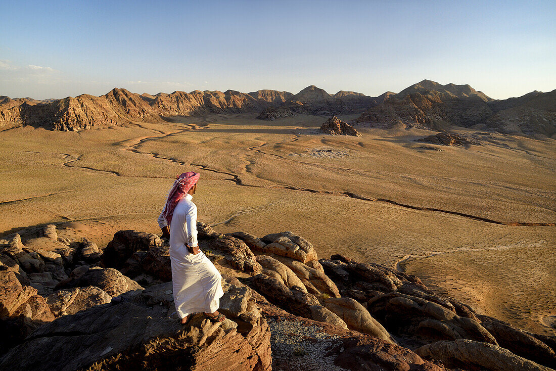 Bedouin and view from the mountain Jebel Khasch. Jordan, Wadi Rum desert, border with Saudi Arabia. Model Released.