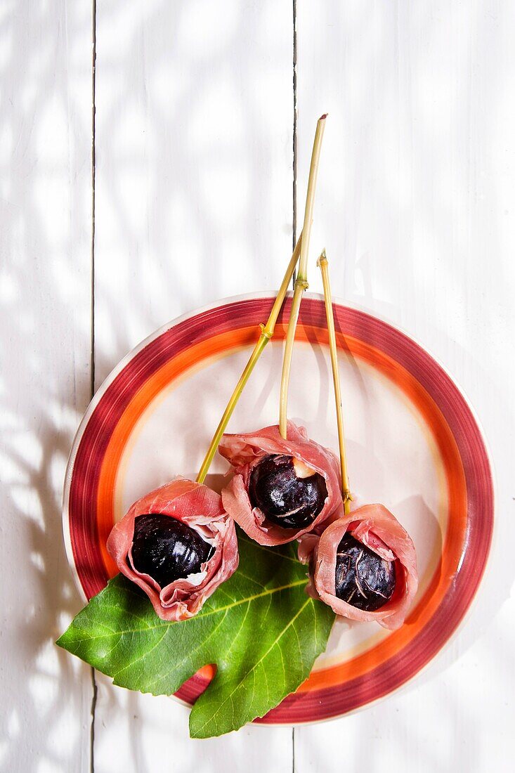 Presentation of dish skewers with ham and figs blacks.