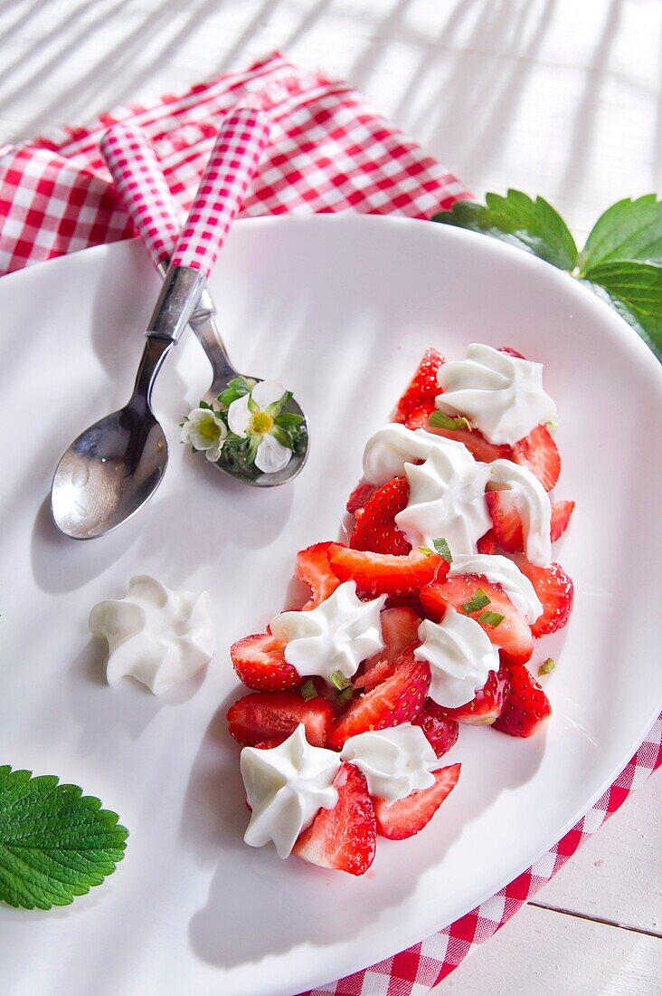 Presentation of the strawberries with cream in ceramic dish.