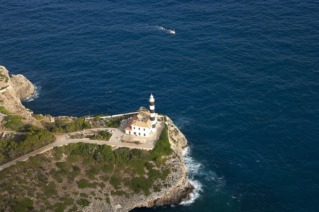Aerial view of a lighthouse with a small boat approaching Port de Soller (Mallorca).